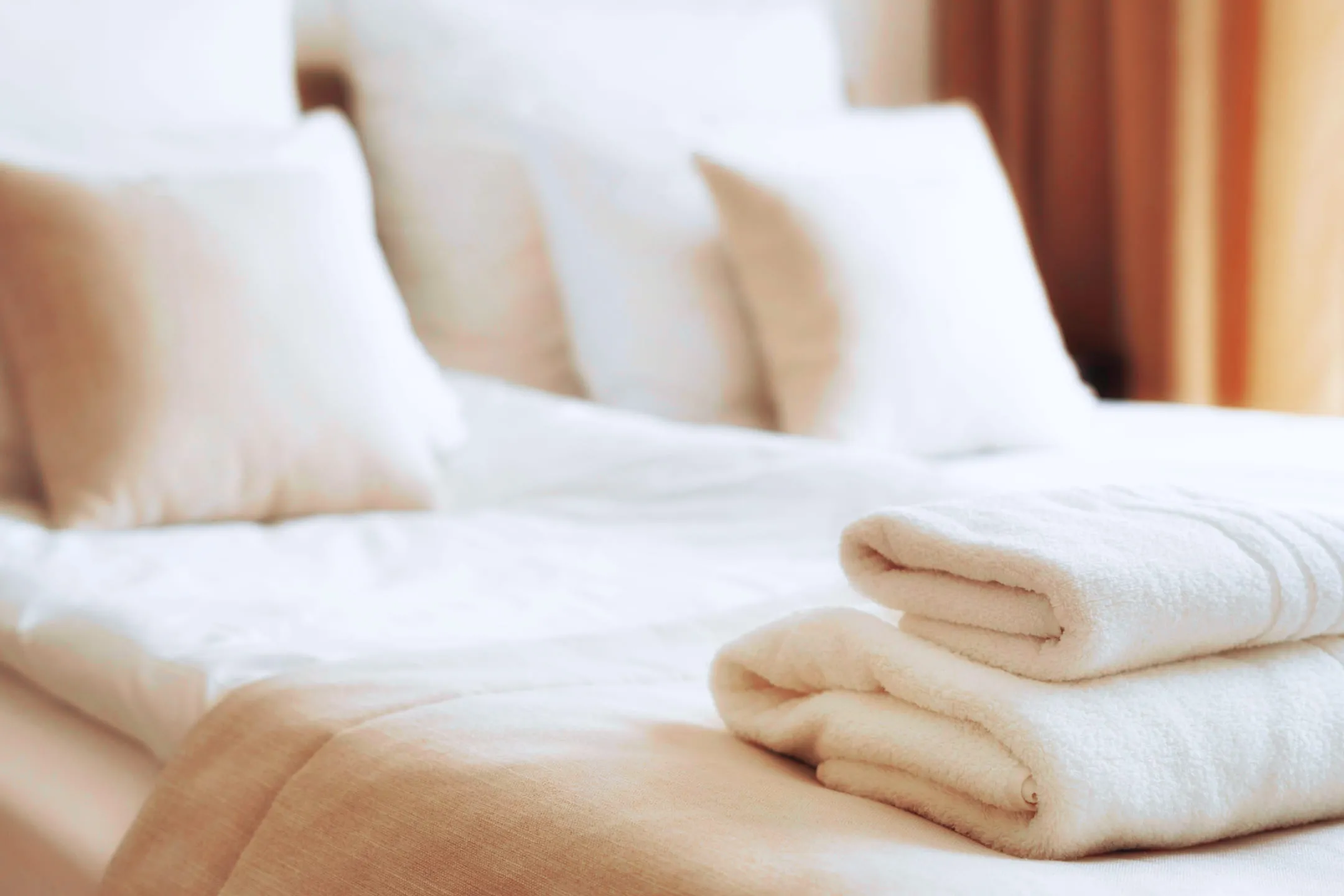Белые полотенца сложены на белой кровати